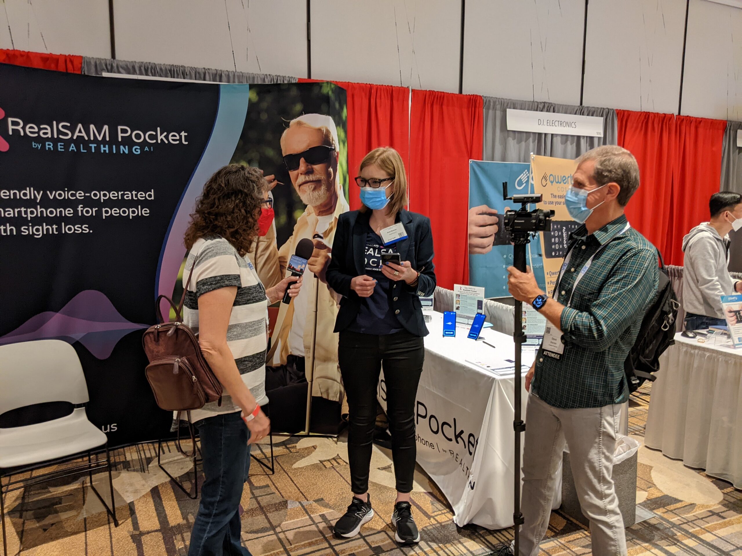 Image of Allison and Steve interviewing Anat on the background of the RealSAM Booth at the CSUN ATC 2022