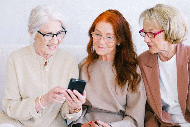 A picture of three senior women looking at a phone.